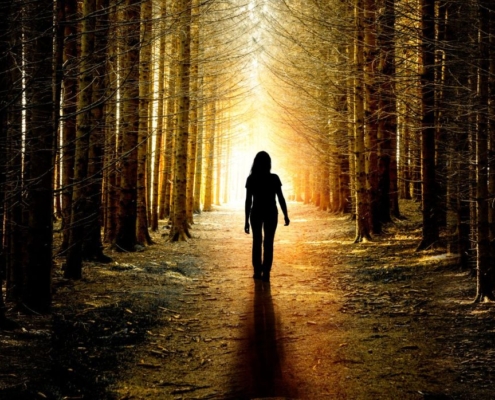Woman walking in forest sunrise